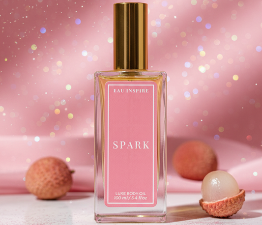 Body oil bottle labeled 'Spark' with a pink label on a glittery pink background